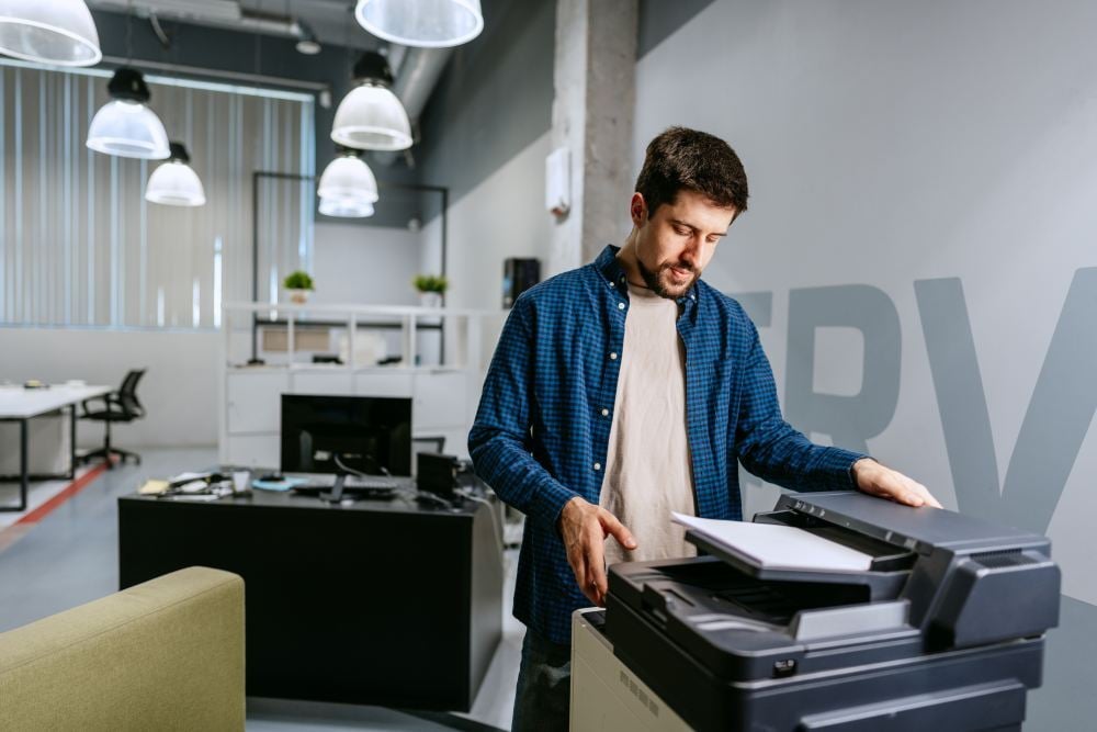 Hombre utilizando una impresora multifunción profesional en una oficina moderna