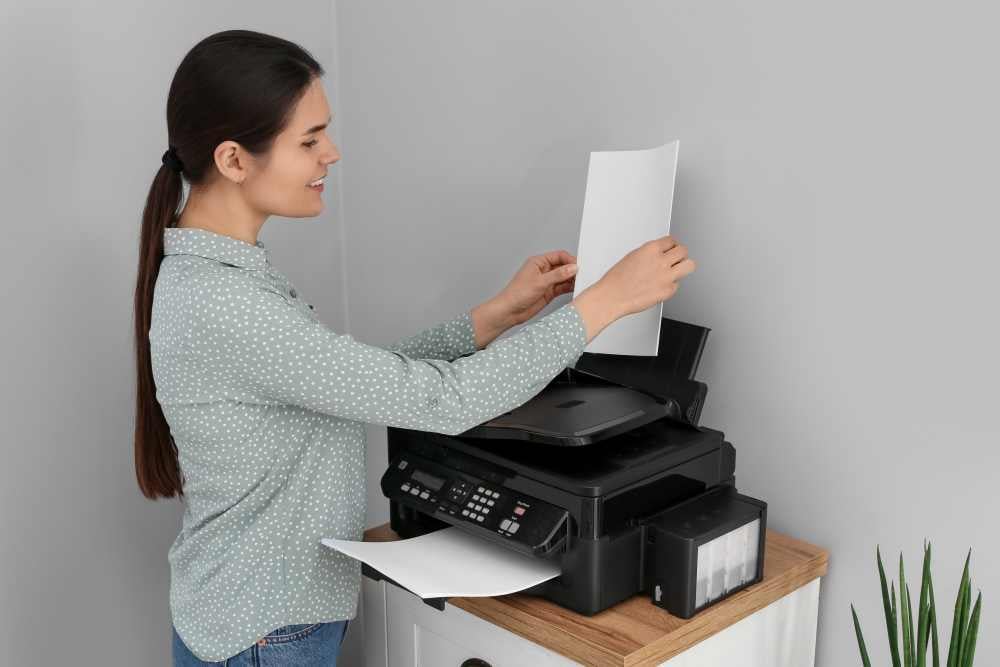 Persona utilizando una impresora multifunción en una oficina pequeña para imprimir documentos